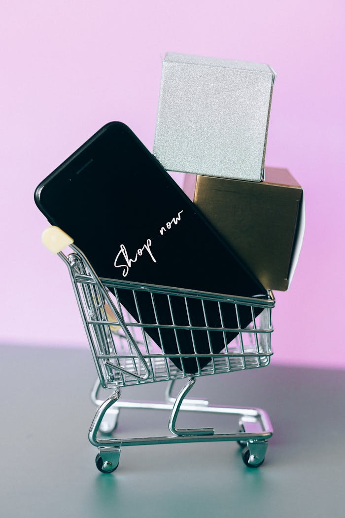 home-img Mini shopping cart with smartphone and gift boxes, symbolizing online shopping.
